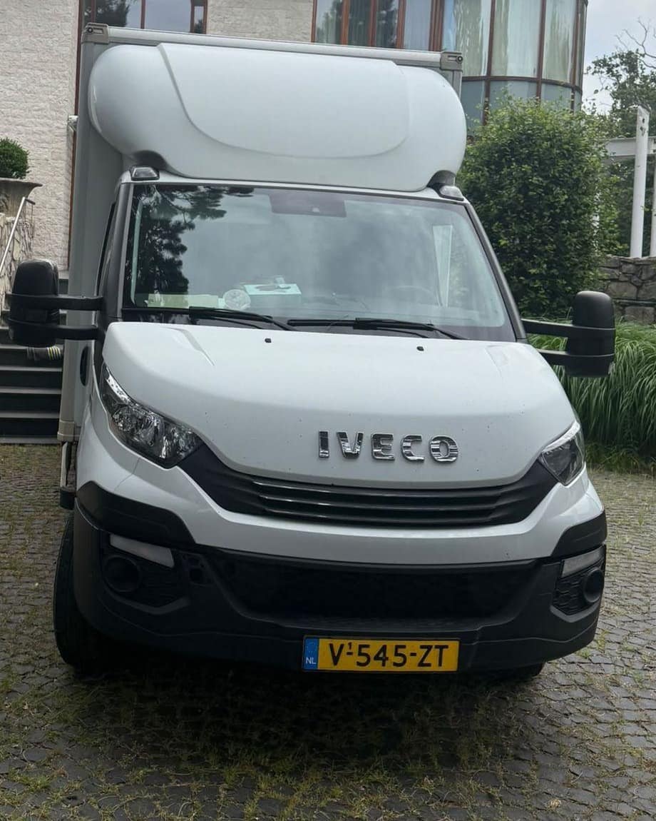 Gesloten verhuiswagen met laadklep, geparkeerd op een oprit voor een woning