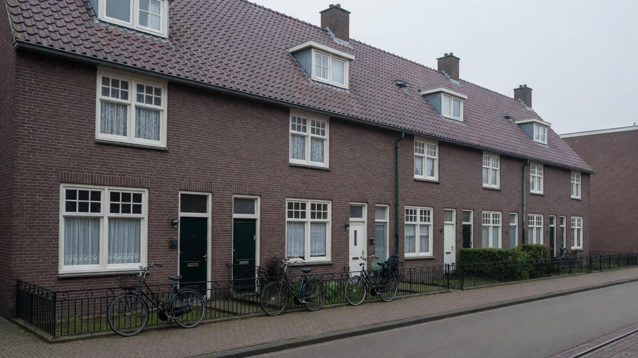Rij jaren-30 woningen met steile pannendaken en fietsen tegen het hek