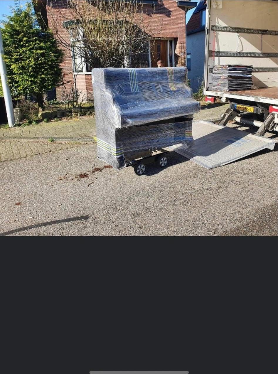 Strak ingepakte piano op de pianowagen naast de laadklep
